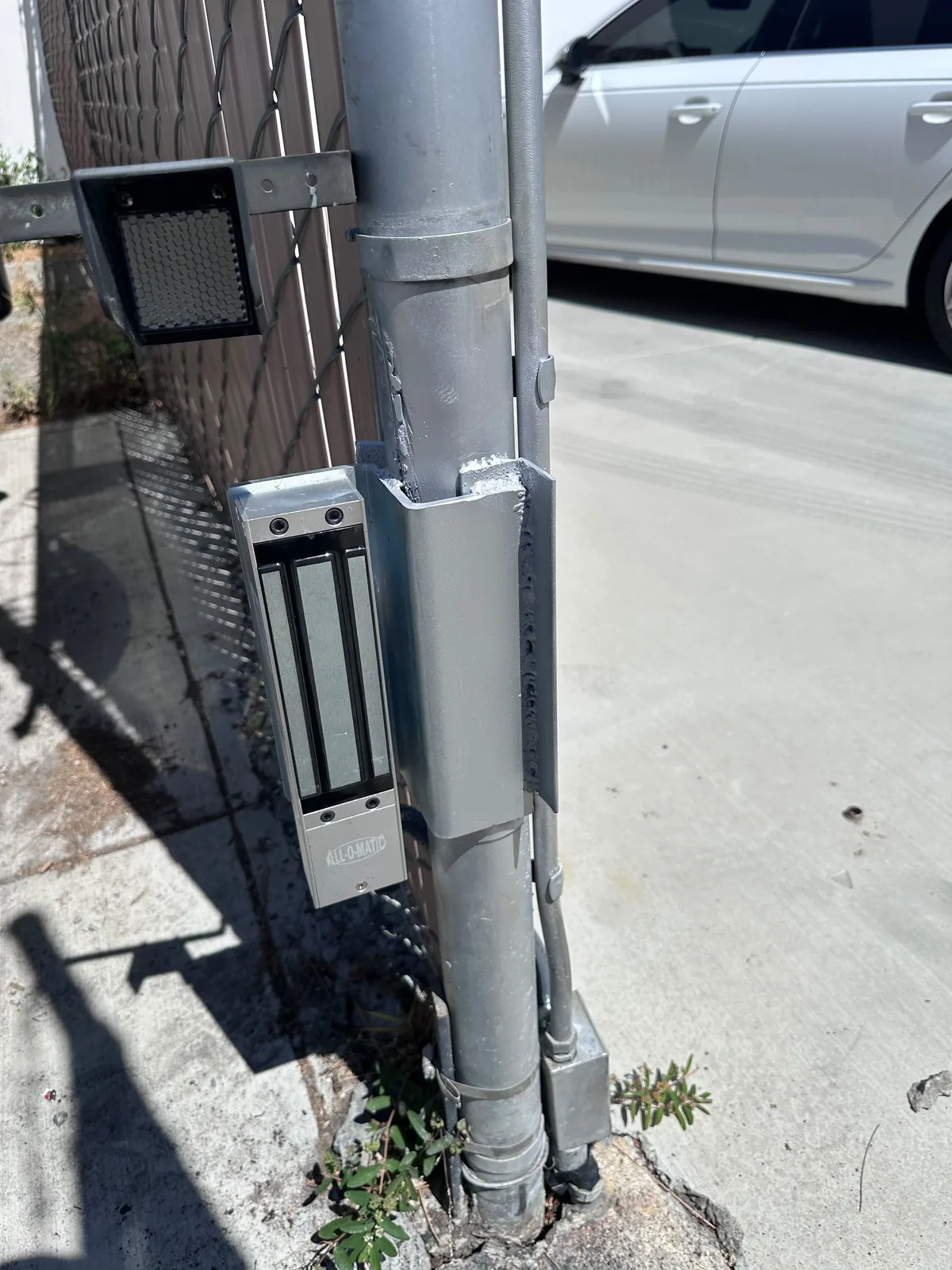 All O Matic magnetic gate lock on a metal post with a reflector mounted above the hardware