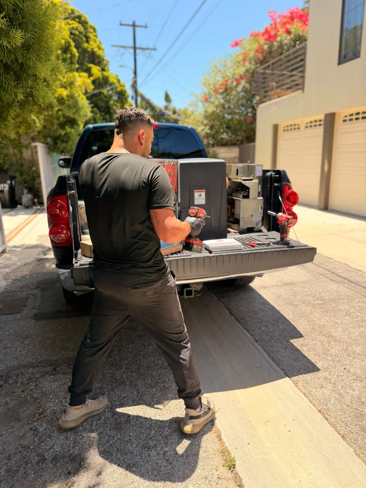 Technician preparing gate operator equipment and tools at the tailgate of a service pickup